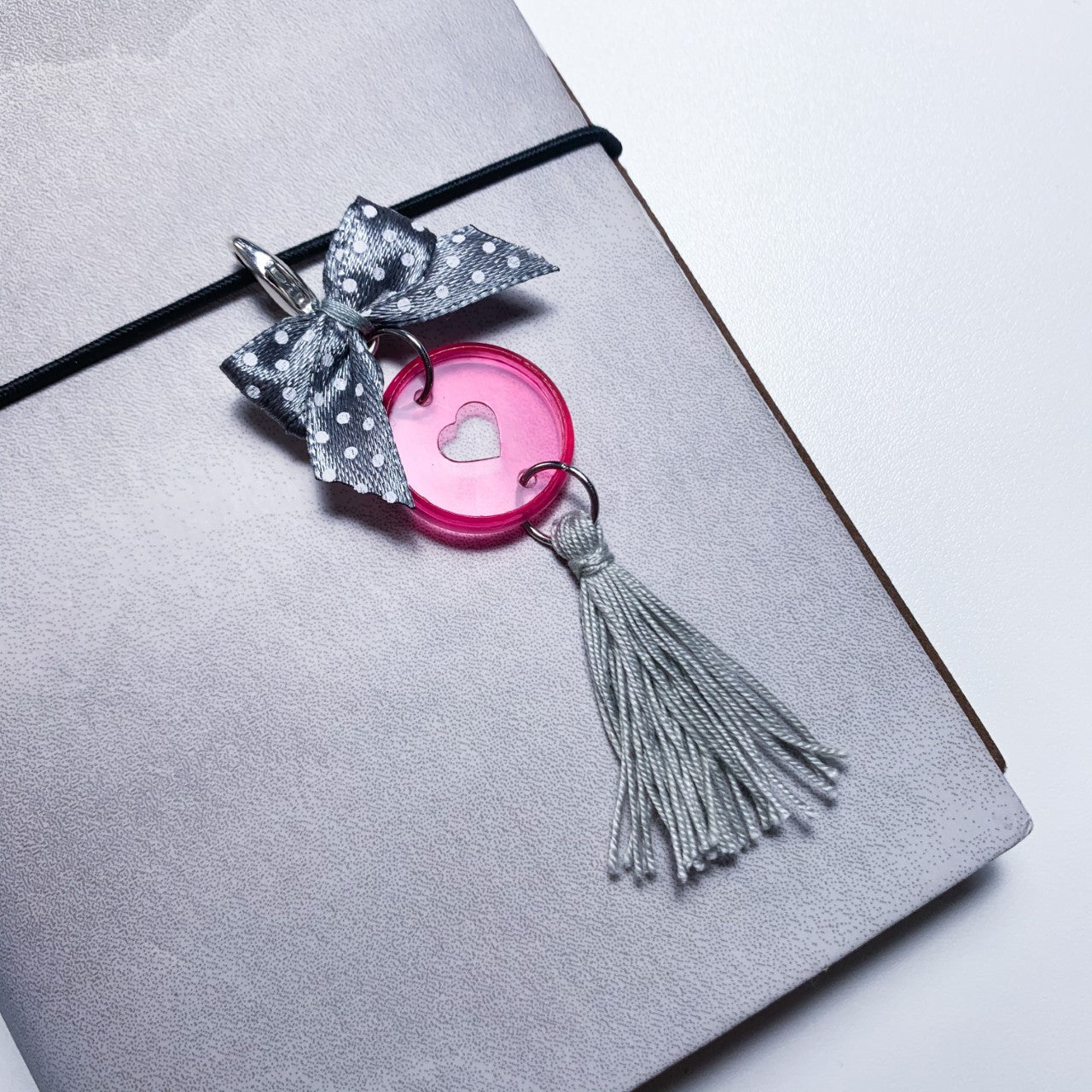 Pink disc charm with grey tassel and bow